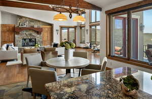 Dining room with beam ceiling, high vaulted ceiling, wood finished floors, and a fireplace