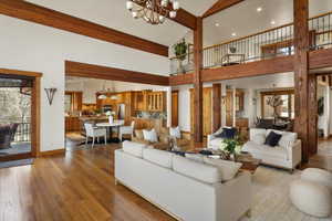 Living room featuring high vaulted ceiling, baseboards, dark wood finished floors, and a notable chandelier