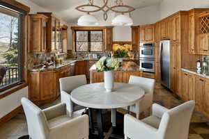 Kitchen featuring decorative backsplash, glass insert cabinets, a center island, brown cabinets, and appliances with stainless steel finishes