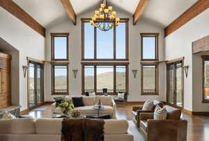 Living room with an inviting chandelier, beam ceiling, high vaulted ceiling, and wood finished floors