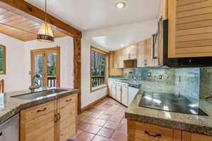 Kitchen with tasteful backsplash, black electric stovetop, plenty of natural light, and a sink