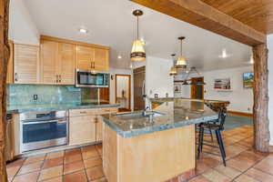 Kitchen featuring tasteful backsplash, light brown cabinets, stainless steel appliances, light tile patterned floors, and a sink