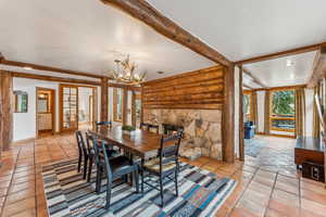 Dining room with log walls, light tile patterned flooring, a chandelier, and baseboards
