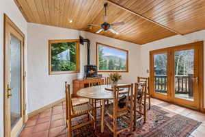 Dining space featuring plenty of natural light, a wood stove, and wooden ceiling