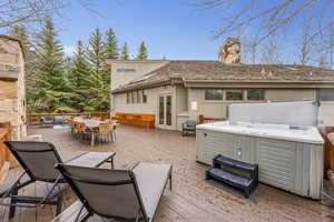 Rear view of house with a deck, a chimney, french doors, and a hot tub