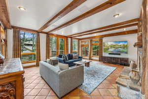 Living room with beamed ceiling, recessed lighting, light tile patterned floors, and baseboards