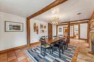 Dining room featuring an inviting chandelier, light tile patterned floors, beamed ceiling, and baseboards