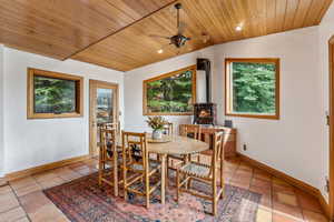 Tiled dining space with baseboards, wooden ceiling, ceiling fan, and vaulted ceiling