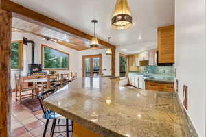 Kitchen featuring decorative backsplash, a wood stove, a sink, french doors, and a peninsula