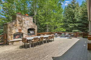 View of patio with an outdoor stone fireplace, outdoor dining area, a deck, and area for grilling