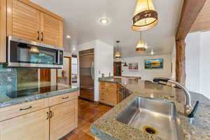 Kitchen featuring recessed lighting, a sink, backsplash, appliances with stainless steel finishes, and dark tile patterned flooring