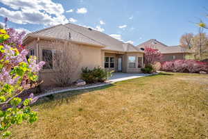 Rear view of property featuring stucco siding, a yard, and a patio area