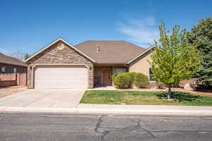 Single story home with a garage, a front lawn, stone siding, and concrete driveway