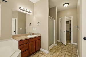 Full bath with vanity, stone finish floor, a shower stall, and a walk in closet