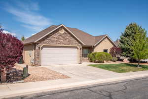 Single story home with concrete driveway, a garage, stone siding, and stucco siding