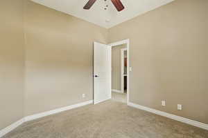 Empty room with baseboards, ceiling fan, and light carpet