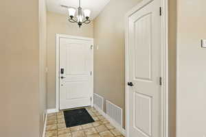 Doorway with a chandelier, baseboards, and visible vents