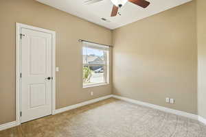 Carpeted spare room with a ceiling fan, baseboards, and visible vents
