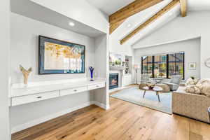 Living area with a fireplace with flush hearth, light wood-type flooring, high vaulted ceiling, beamed ceiling, and recessed lighting