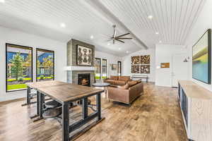 Living room featuring wood ceiling, a ceiling fan, a tile fireplace, lofted ceiling with beams, and light wood finished floors