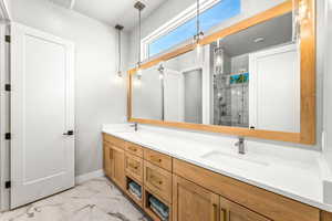 Bathroom featuring double vanity, a sink, marble finish floor, and a stall shower
