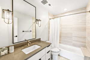 Bathroom with vanity, shower / bath combo with shower curtain, toilet, and visible vents