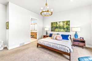 Carpeted bedroom featuring connected bathroom, a notable chandelier, recessed lighting, baseboards, and visible vents