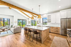 Kitchen with beam ceiling, glass insert cabinets, a center island, recessed lighting, and stainless steel appliances