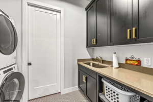 Laundry room featuring a sink, baseboards, stacked washer / drying machine, and cabinet space