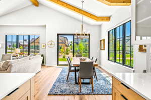 Dining space with beamed ceiling, an inviting chandelier, light wood finished floors, and high vaulted ceiling