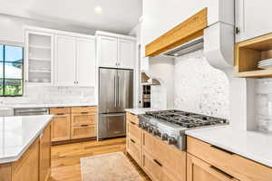 Kitchen featuring light countertops, light wood-style flooring, appliances with stainless steel finishes, and backsplash
