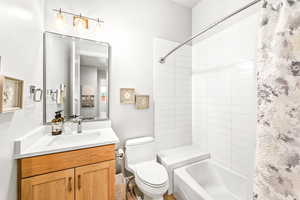 Bathroom featuring vanity, toilet, and shower / bath combination with curtain