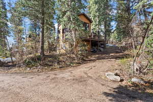 View of side of home featuring a deck and dirt driveway