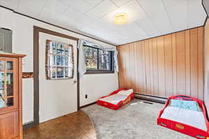 Bedroom with wood walls and a baseboard radiator