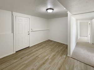 Spare room featuring baseboards, a textured ceiling, and wood finished floors