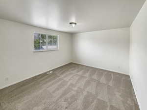 Carpeted spare room featuring baseboards and visible vents