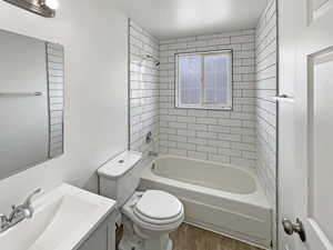 Full bathroom with toilet, tub / shower combination, wood finished floors, and vanity