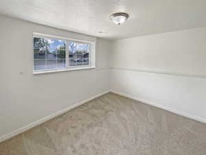 Carpeted empty room featuring baseboards and a textured ceiling