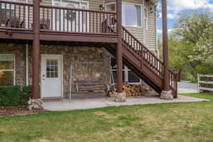 Rear view of house featuring a lawn, stairs, and stone siding