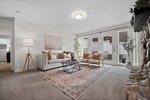 Carpeted living area featuring french doors and baseboards