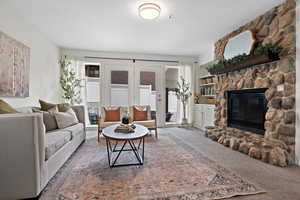 Living room featuring carpet and a stone fireplace