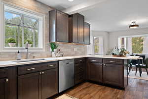 Kitchen featuring a sink, backsplash, a peninsula, light countertops, and stainless steel dishwasher