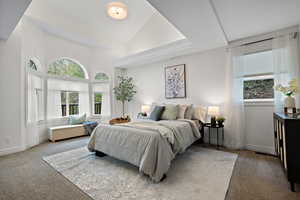 Master bedroom featuring baseboards, multiple windows, and lofted ceiling
