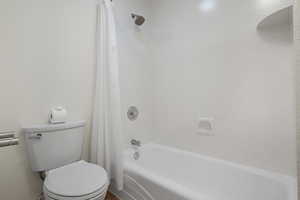Bathroom with shower / bath combination with curtain and toilet
