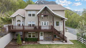Back of property with fence, a patio, a wooden deck, and stone siding