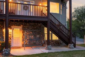 Exterior entry at dusk with stone siding and a balcony