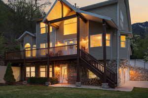 Back of house featuring stairway, a yard, a wooden deck, and stone siding