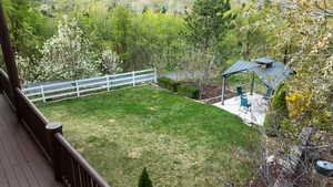 View of yard featuring a view of trees, a gazebo, a fenced backyard, and a patio area