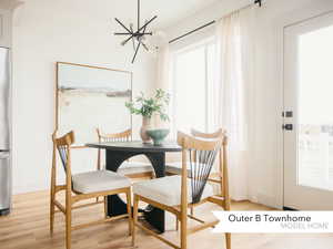 Dining room with baseboards, a notable chandelier, and light wood-type flooring