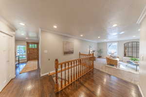 Corridor featuring baseboards, wood finished floors, a wealth of natural light, and an upstairs landing